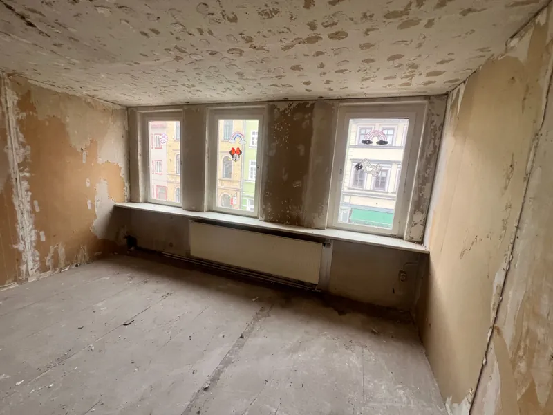 Zimmer im Bestand: abgeplatzter Putz, alte Fensterbänke, Heizkörper