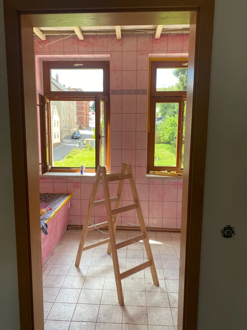 Bad im Bestand: rosa Fliesen, alte Sanitärobjekte, zwei Holzfenster