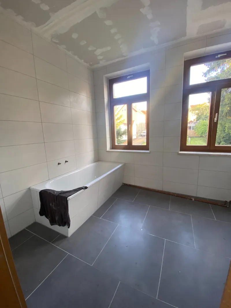 Fertiges Bad: Wanne, Vorwand, Bodenfliesen — gleicher Blick wie vorher